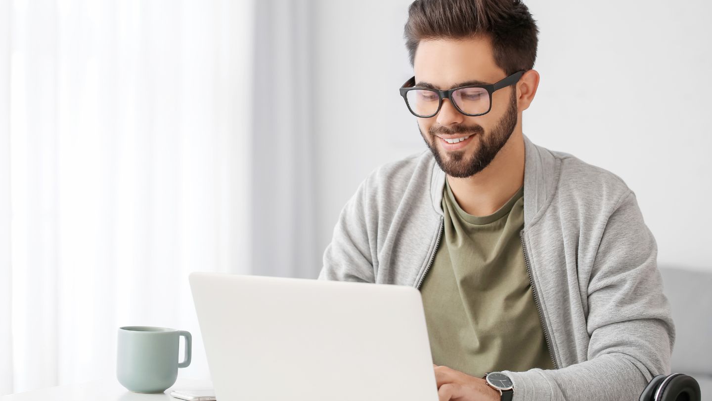Man Smiling While Using Laptop at Home