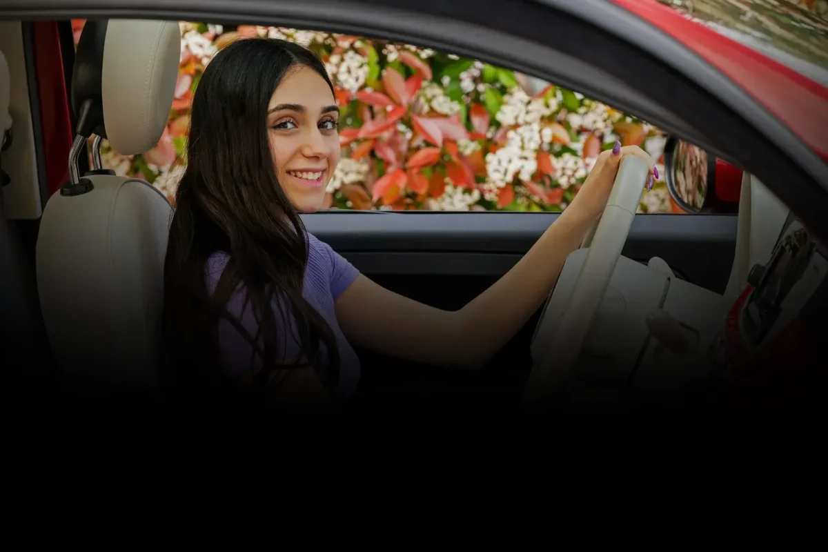 smiling young woman drives car