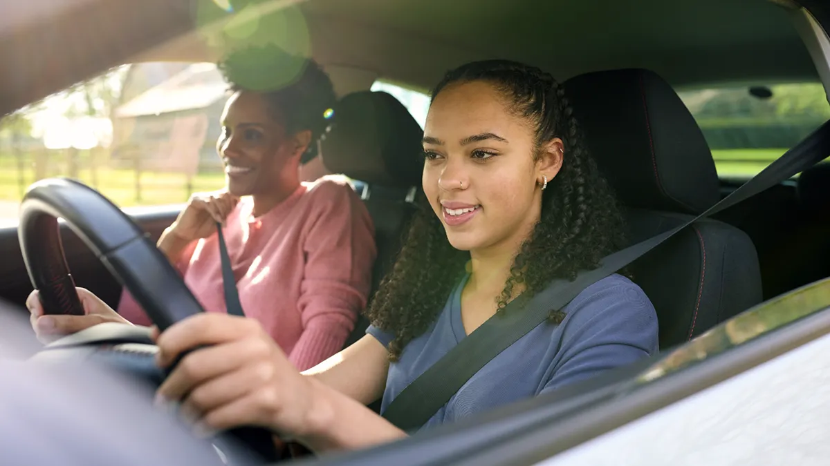 teenager driving vehicle with her mother