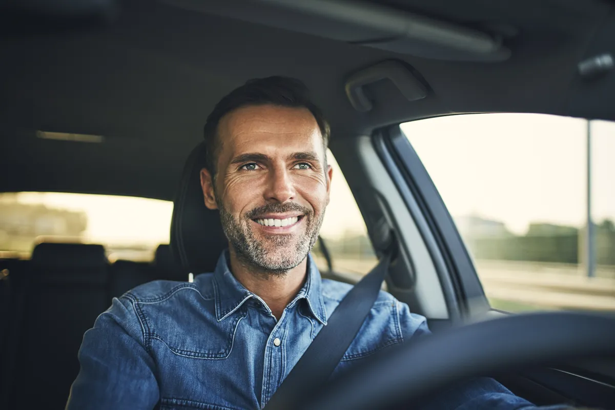 smiling man driving car on sunny day